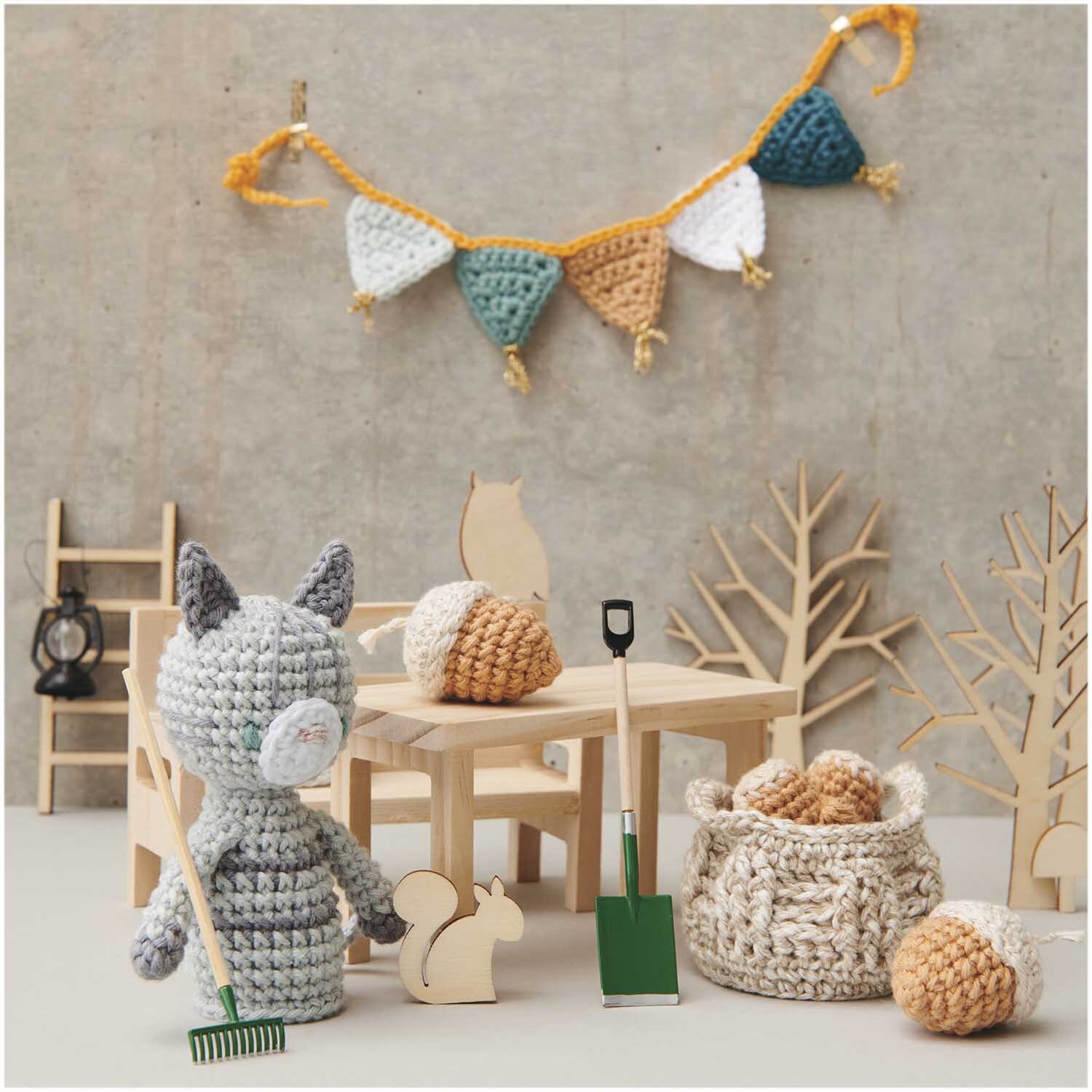 Miniatur Tisch rechteckig 12x6x6,5cm von Rico Design Miniatur Tisch rechteckig mit gehäkelten Dekorationen, Holzfiguren und bunter Wimpelkette im Hintergrund.