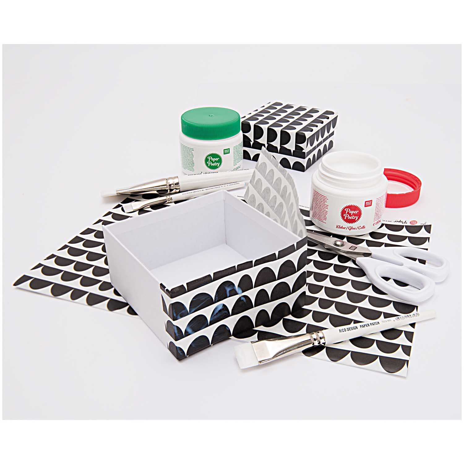 Paper Poetry Kleber: Bastelset mit Kleber, Pinseln, Schere und gemusterten Boxen von Rico Design.