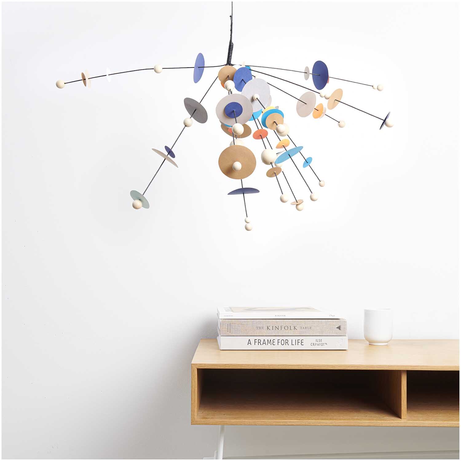 Papierdraht 1,8mm 1m 10 Stück Farbe Schwarz von Rico Design Papierdraht 1,8mm 1m 10 Stück von Rico Design in Schwarz, dekoriert mit bunten Holzscheiben, hängt über einem modernen Tisch mit Büchern.