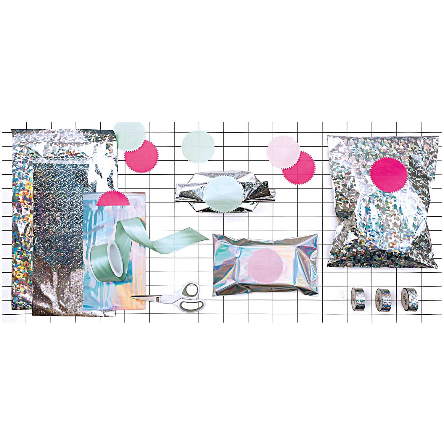 Paper Poetry Holographic Tape Kristall silber 19mm 10m von Rico Design Paper Poetry Holographic Tape Kristall silber 19mm 10m von Rico Design, umgeben von schimmernden Verpackungen und bunten Dekorationen auf einem Gitter.