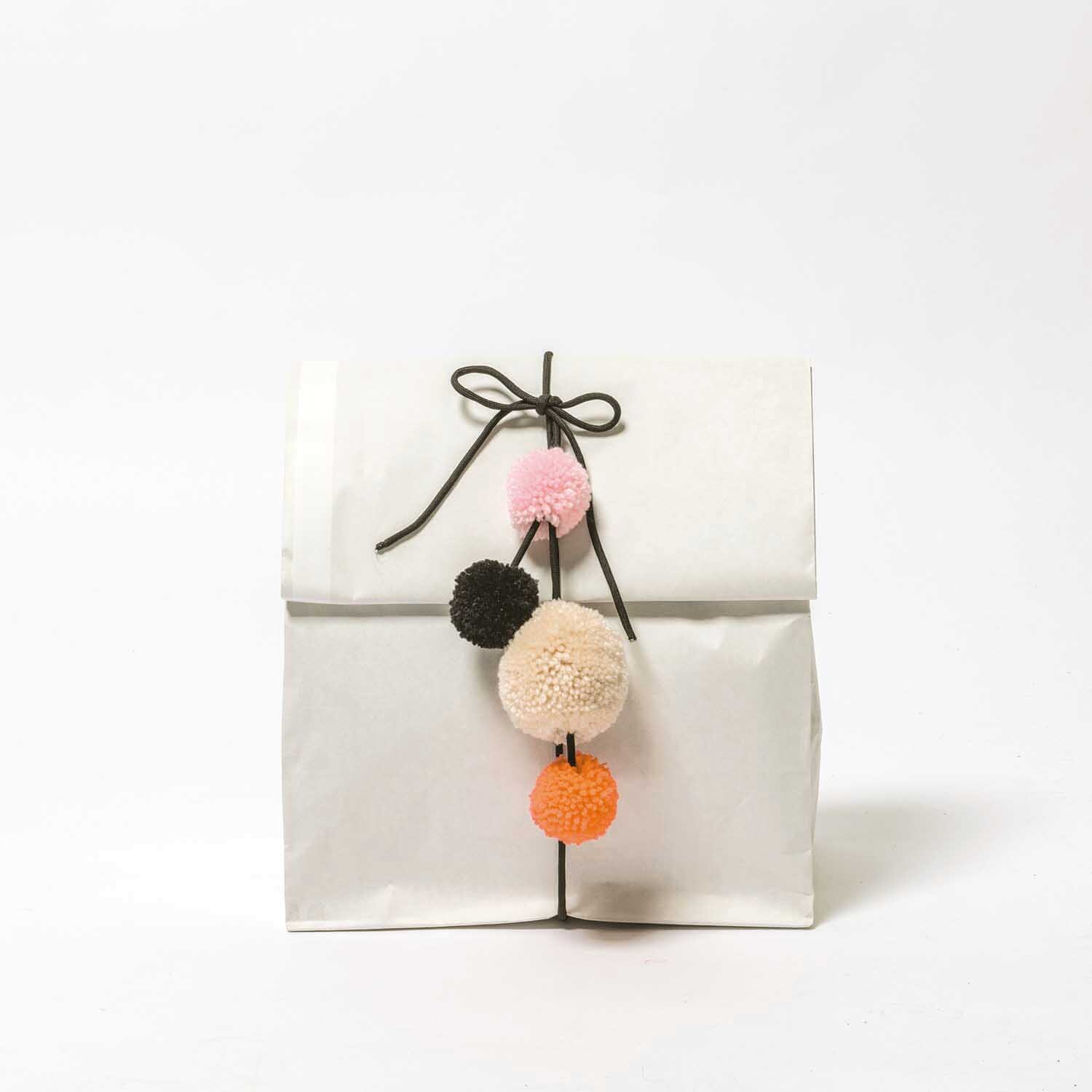 Garn Pompons 24 Stück Farbe Natur Mix von Rico Design Garn Pompons 24 Stück: Weiße Tüte mit bunten Pompons in Rot, Orange und Schwarz von Rico Design.