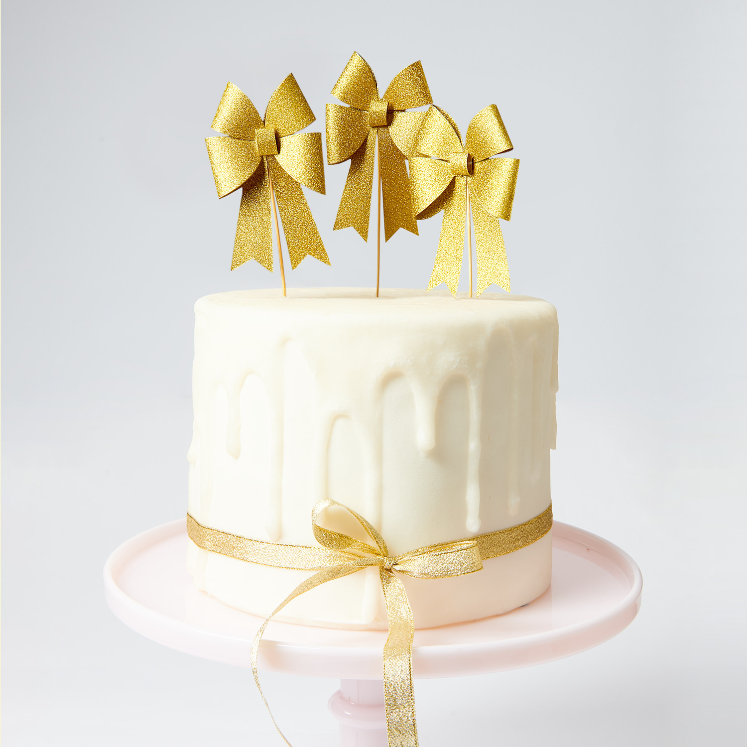 Picker Schleife Gold 7x15cm 6 Stück von Rico Design Picker Schleife Gold: Elegante goldene Schleifen von Rico Design auf einer weißen Torte als Dekoration.