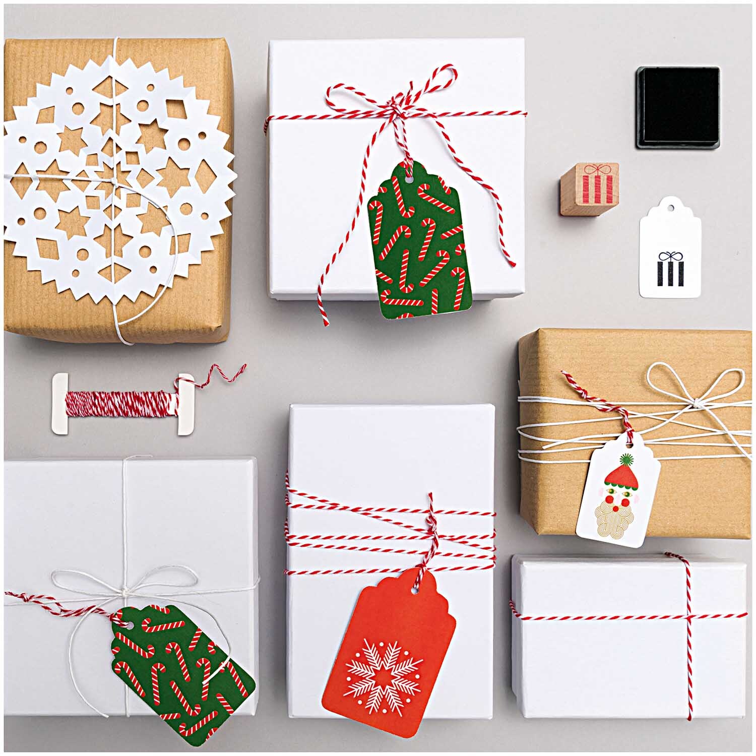 Paper Poetry Packpapier umwickelt Geschenke mit roten Bändern und weihnachtlichen Anhängern.