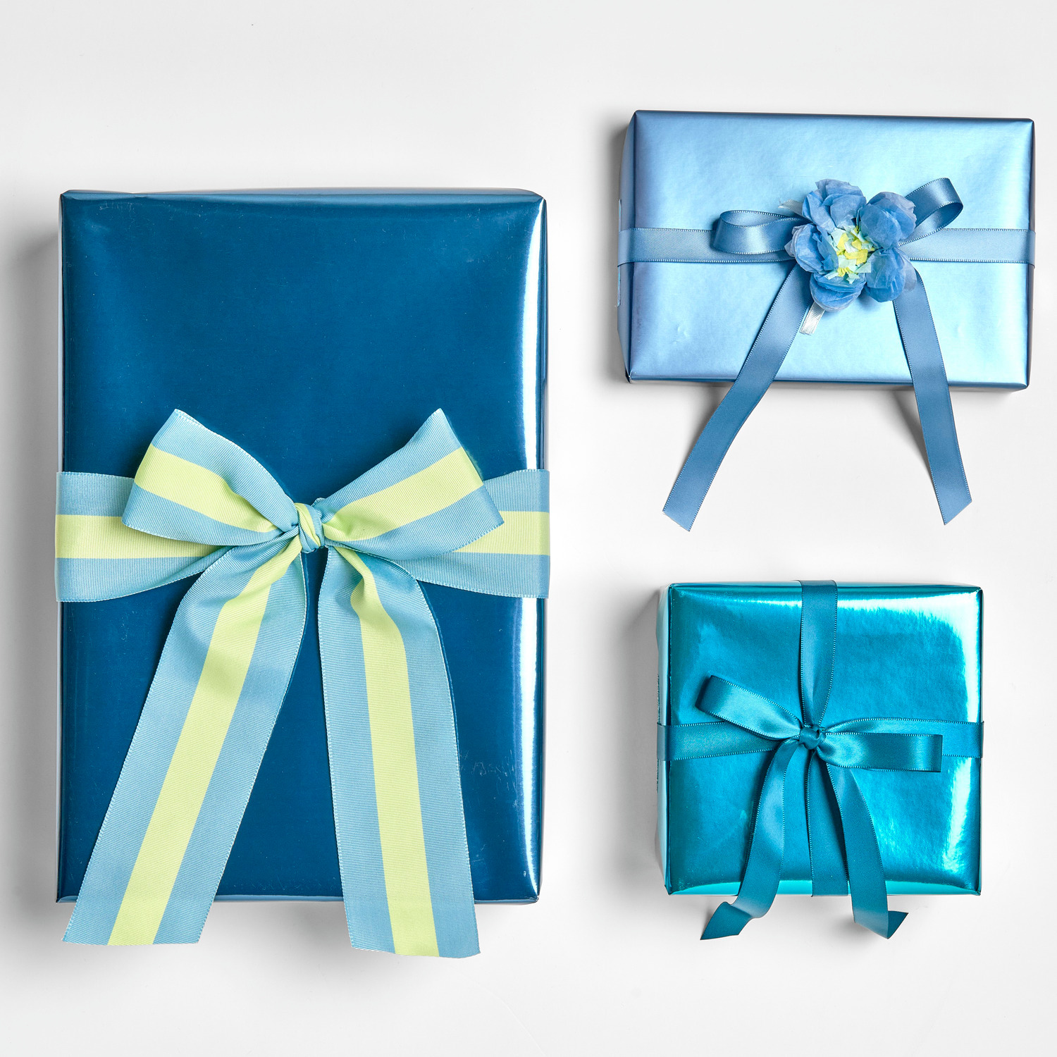 Geschenkpapier Metallic 70cm 2m 80g/m² Farbe Petrol von Rico Design Geschenkpapier Metallic Matt: Drei in Blau verpackte Geschenke mit Schleifen, ideal für festliche Anlässe.
