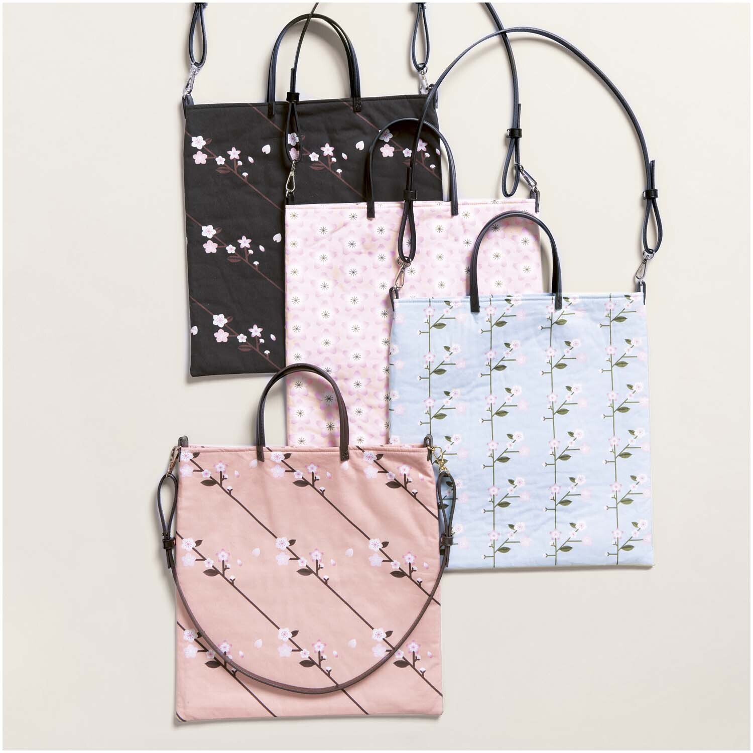 Meterware Baumwoll-Popelin schwarz Sakura Zweige von Rico Design Meterware Baumwoll-Popelin schwarz Sakura Zweige: Vier Taschen mit floralen Mustern in verschiedenen Farben, ideal für stilvolle Accessoires.