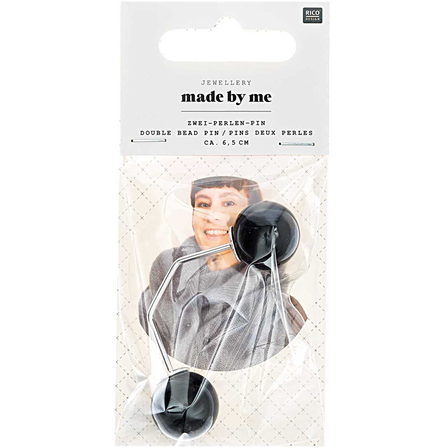 Zwei-Perlen-Pin 65mm 1 Stück Farbe Schwarz von Rico Design Zwei-Perlen-Pin 65mm von Rico Design in Schwarz, präsentiert in einer Verpackung mit lächelndem Model.