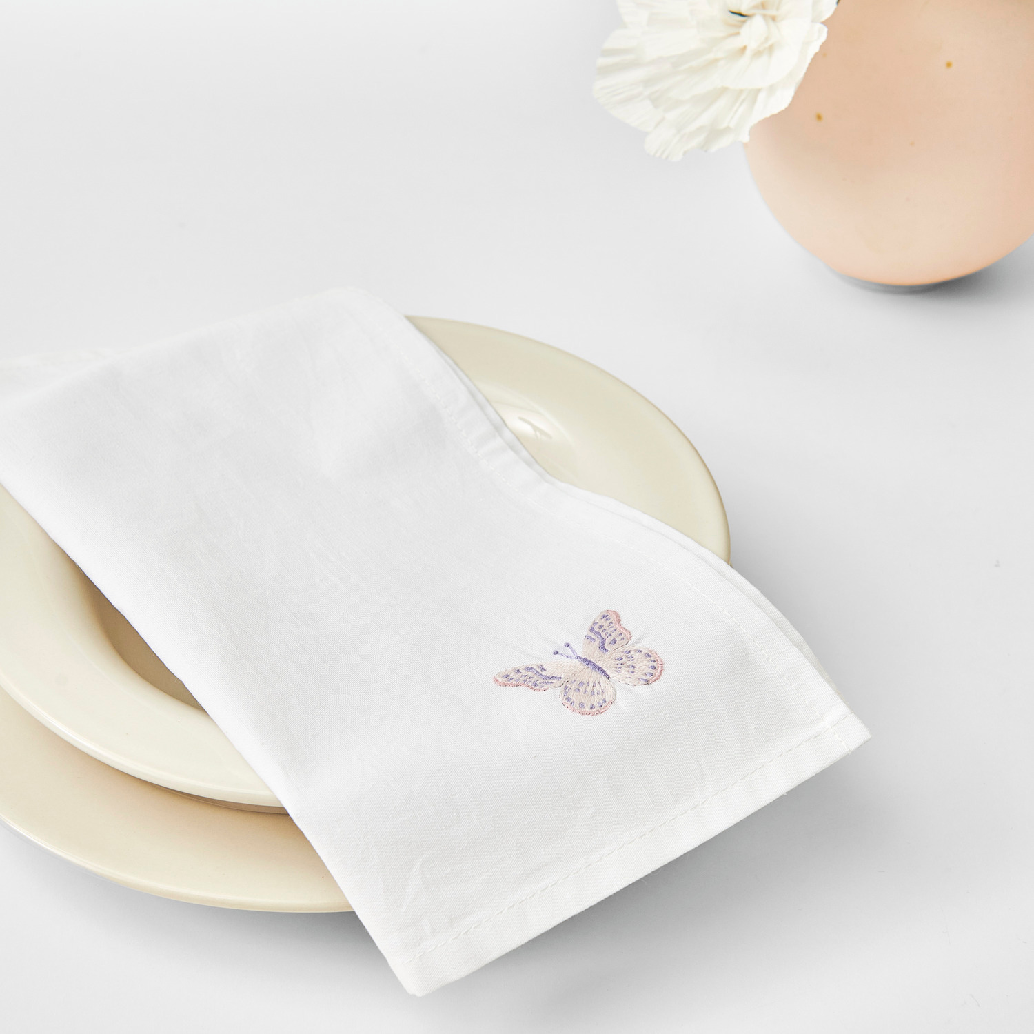 Stoffserviette 2 Stück weiß Größe 30x30cm von Rico Design Stoffserviette 2 Stück weiß von Rico Design, dekoriert mit Schmetterlingsmotiv, auf Teller arrangiert.