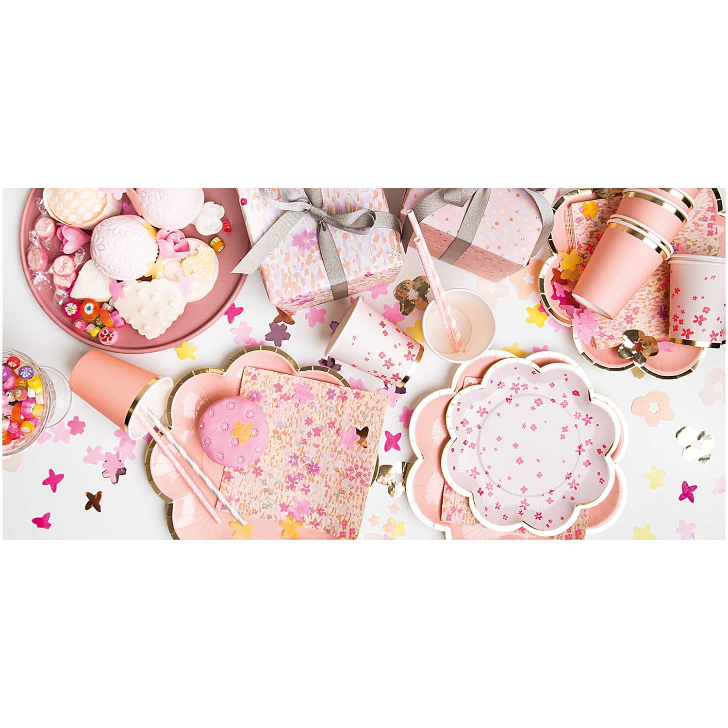 Pappteller Blume Blüten rosa 21cm 12 Stück von Rico Design Pappteller Blume Blüten rosa 21cm 12 Stück, dekoriert mit Partyzubehör und Süßigkeiten auf einem Tisch.