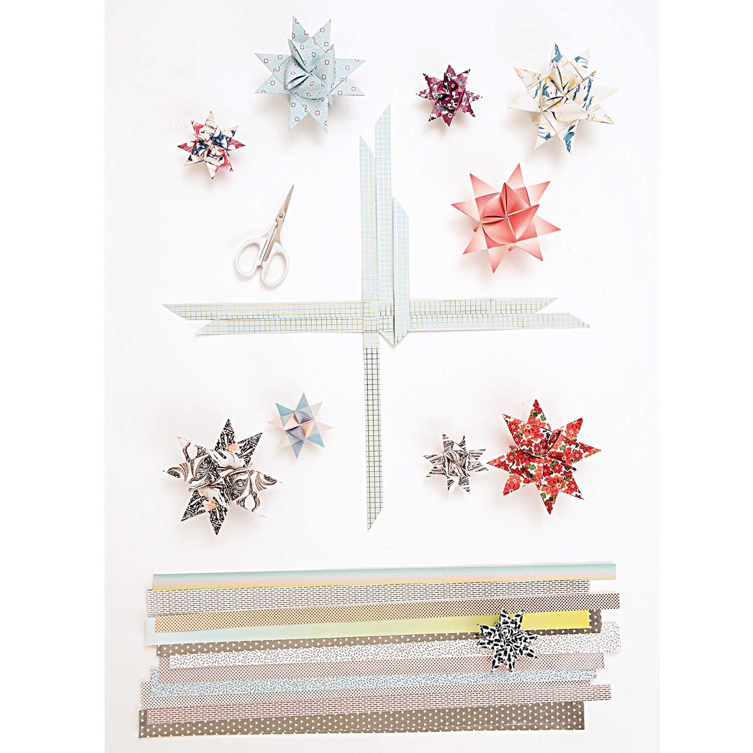 Präzisionsschere klein 10cm von Rico Design Präzisionsschere klein 10cm von Rico Design neben bunten Origami-Sternen und Papierstreifen.