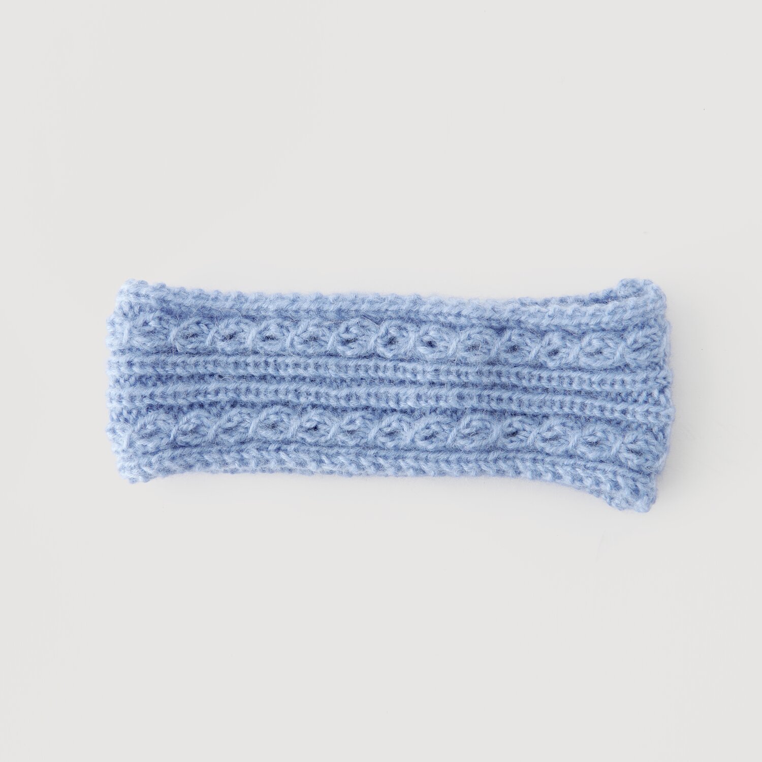 Luxury Merino Alpaca Dream aran 50g 125m Farbe Taubenblau von Rico Design Stirnband aus hellblauer Wolle mit Zopfmuster, Modell Legeware. Ideal für kalte Tage, bietet es stilvollen Schutz. Perfekt für Modebewusste, die Komfort schätzen.