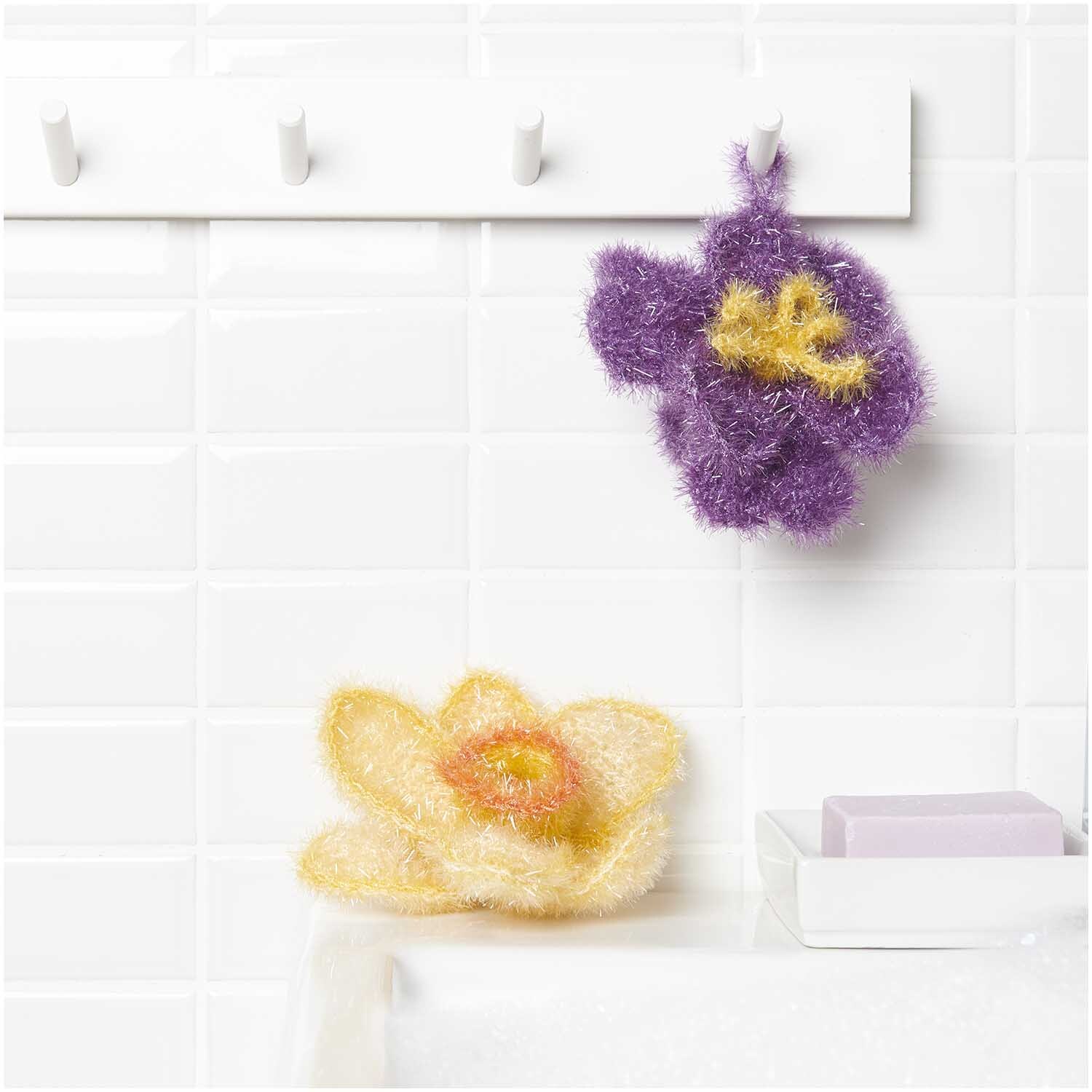 Häkelset Creative Bubble Frühlingsblume von Rico Design Häkelset Creative Bubble Frühlingsblume: Zwei gehäkelte Blumen in Lila und Gelb von Rico Design, dekorativ im Badezimmer platziert.
