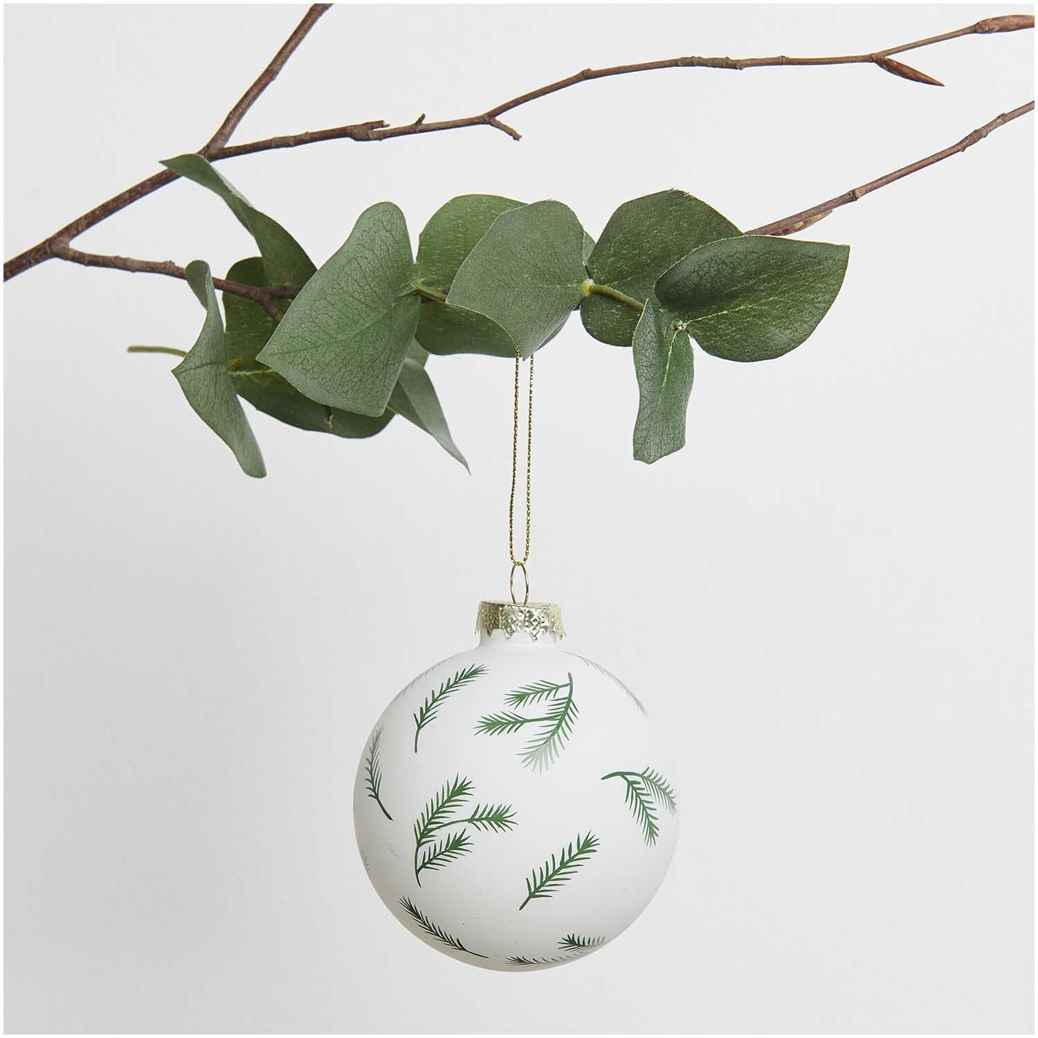 Glaskugel Baumschmuck mit Tannenzweigen grün Ø 8cm von Rico Design Glaskugel Baumschmuck mit Tannenzweigen hängt an einem Ast, verziert mit grünen Zweigen.