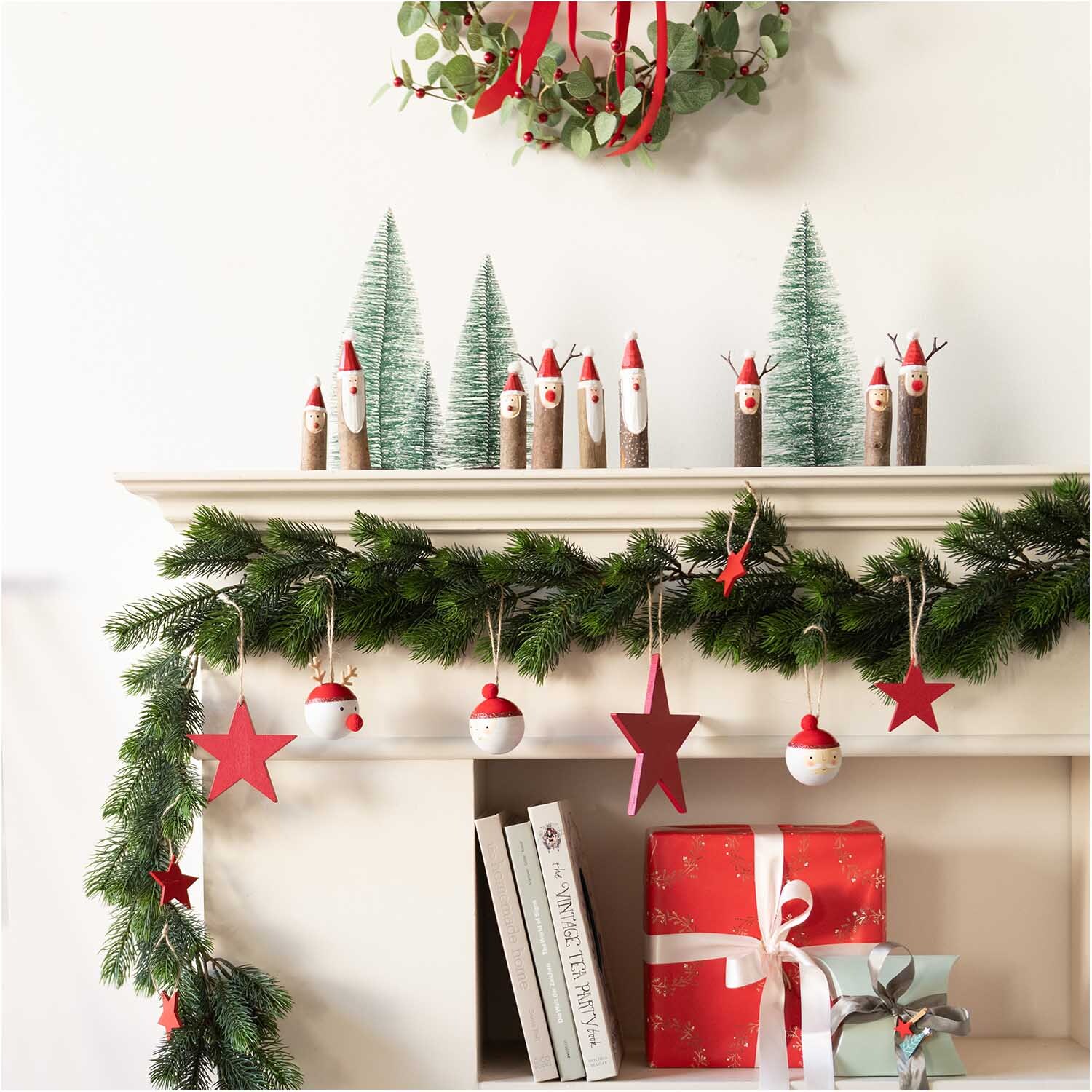 Holzstreu Tannenbaum 15x30mm 48 Stück von Rico Design Holzstreu Tannenbaum 15x30mm 48 Stück: Festliche Dekoration mit grünen Tannenbäumen und roten Akzenten auf einem Kaminsims.