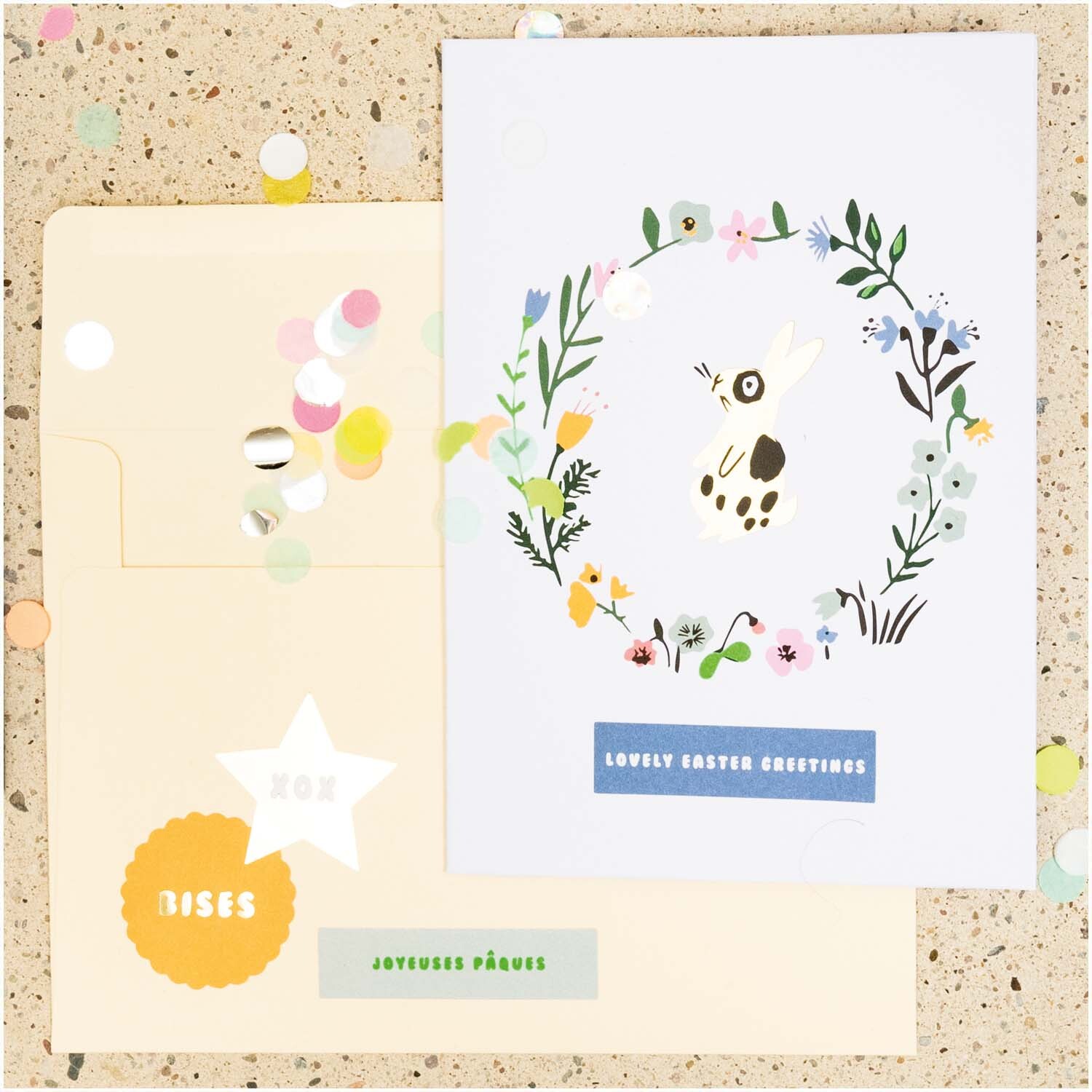 Paper Poetry Grußkartenset Bunny Hop Blumenkranz mit Hase von Rico Design Paper Poetry Grußkartenset Bunny Hop Blumenkranz mit Hase zeigt eine Karte mit floralem Kranz und Hase, beige Umschlag, bunte Konfetti.