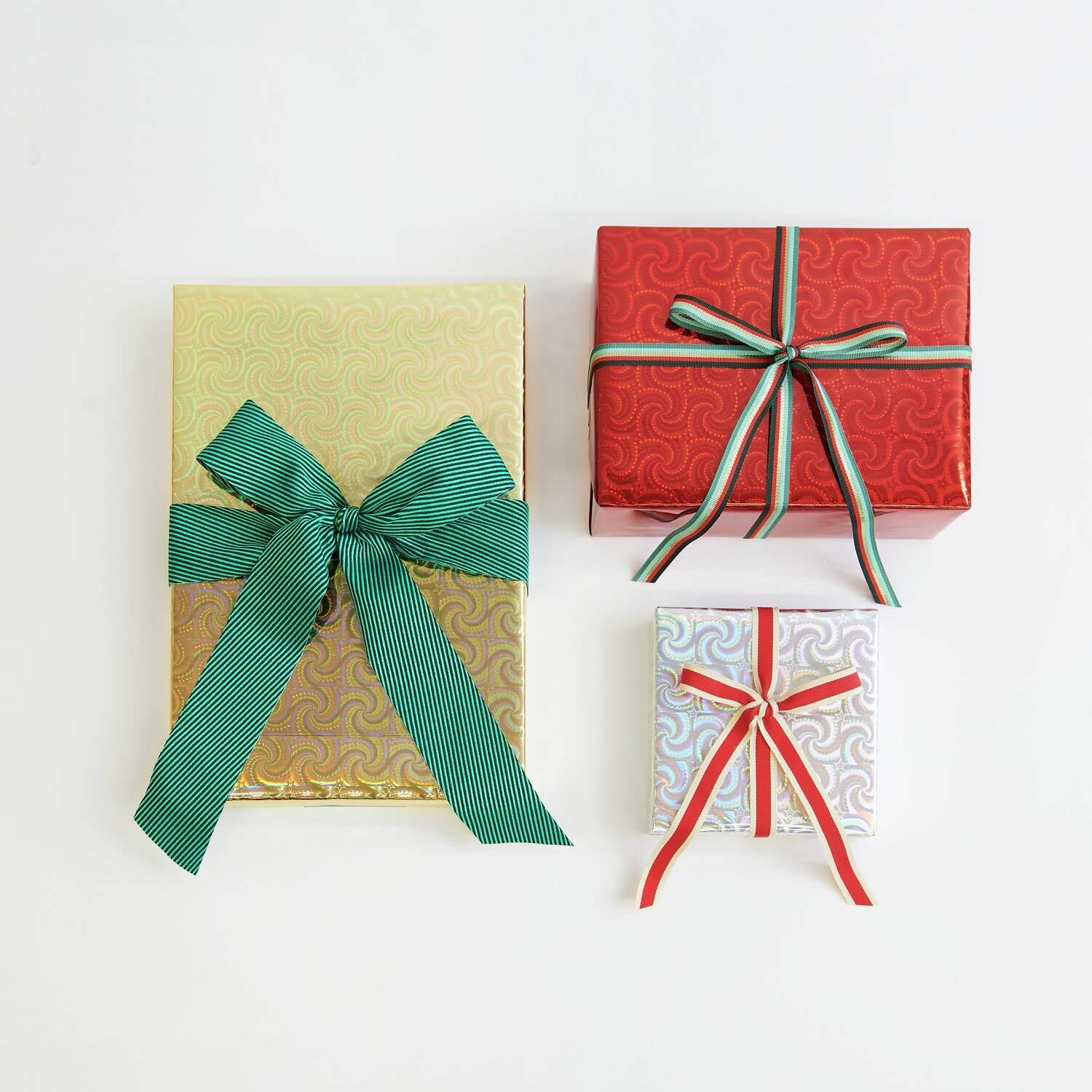 Paper Poetry bande tissée diagonale 50mm 3m Couleur Vert from Rico Design Paper Poetry Geschenkpapier Holographisch mit Sternen Mix: Drei Geschenke in Gold, Rot und Silber, verziert mit grünen und roten Bändern.