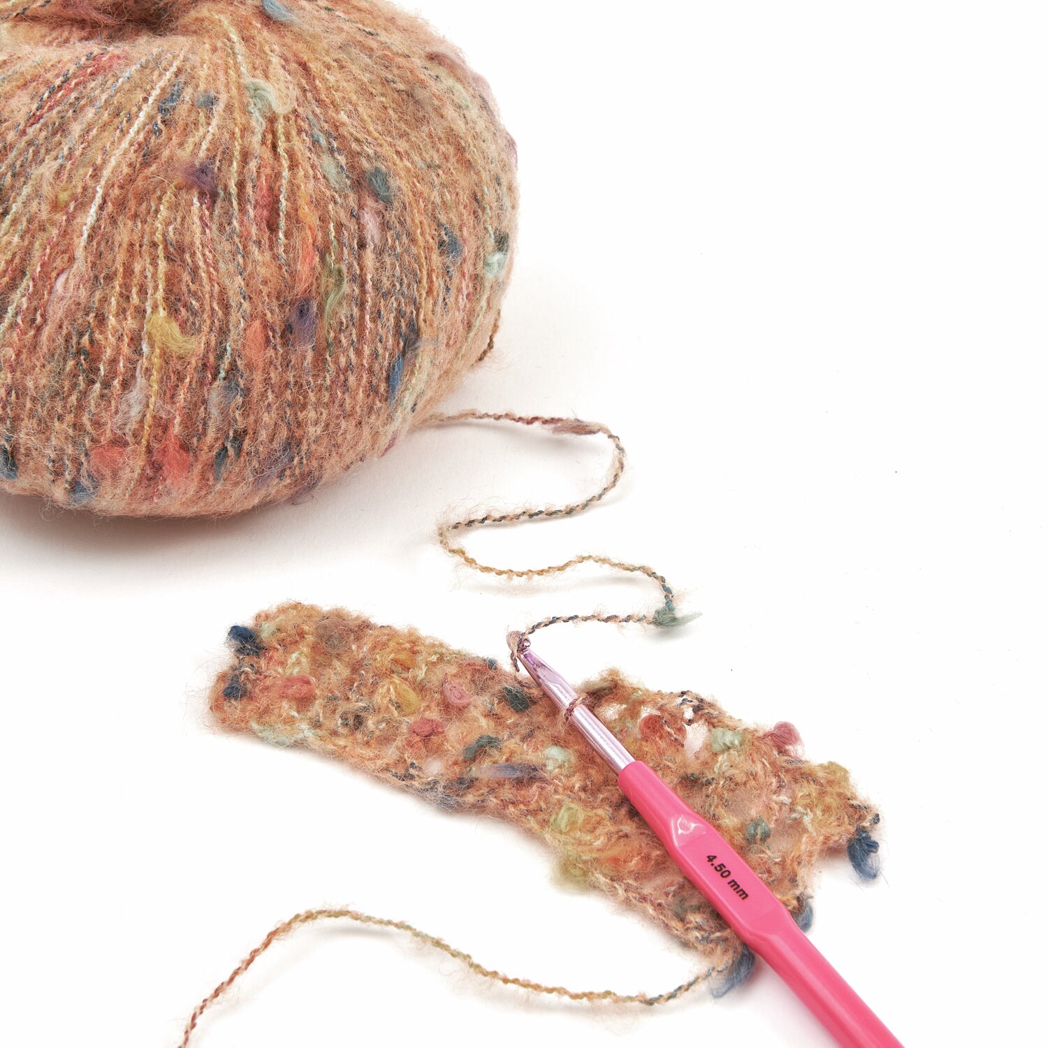 Ein Knäuel mehrfarbiges Garn mit einer gehäkelten Probe und einer rosa Häkelnadel. Ideal für kreative Strickprojekte. Perfekt für Handarbeitsliebhaber, die hochwertige Materialien schätzen.